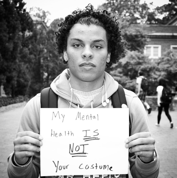 mental health advocate holds sign saying 'my mental health is not your costume'
