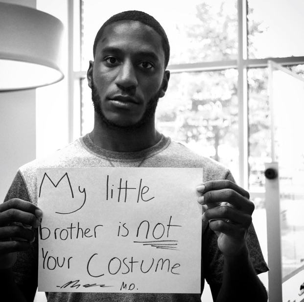 mental health advocate holds sign saying 'my little brother is not your costume'