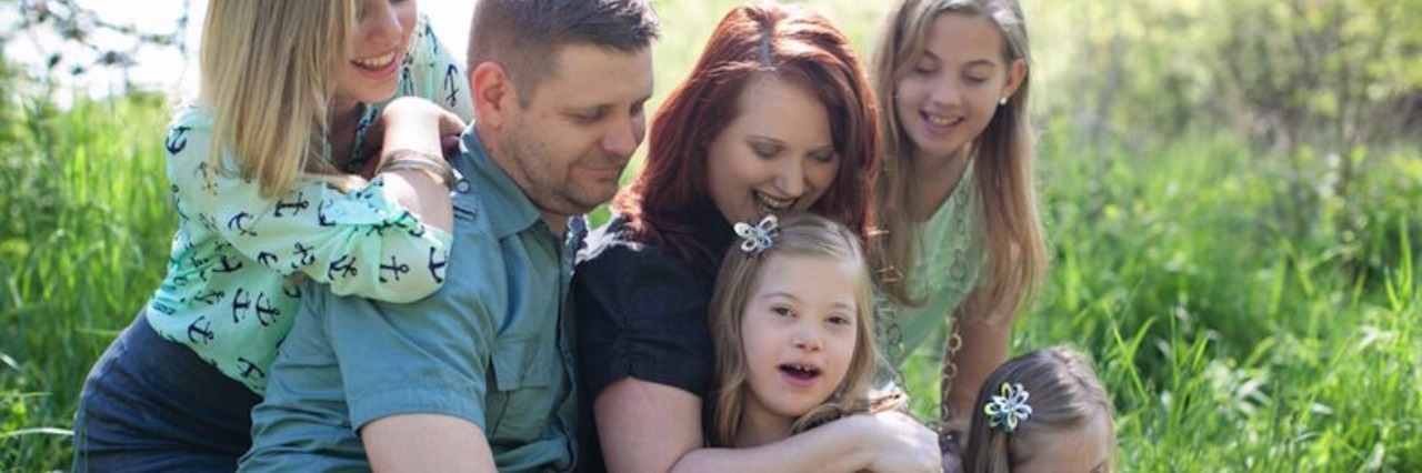 What to Say to Parents of Baby With Down Syndrome parents hugging four young daughters