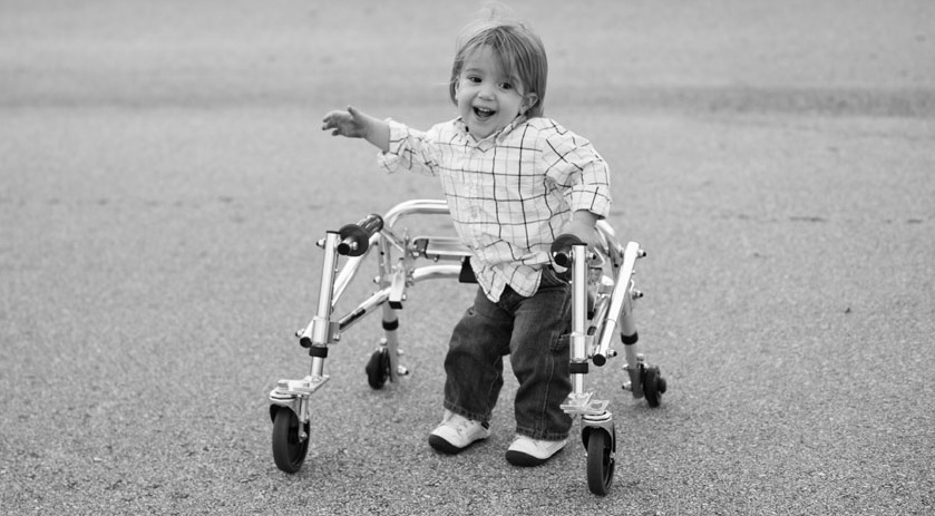 A young boy using a walker.