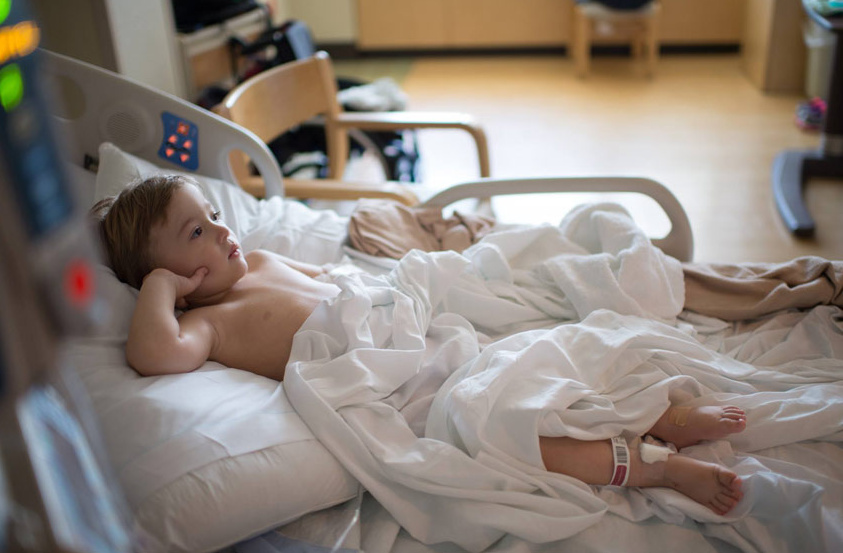 Young boy laying in a hospital bed. 