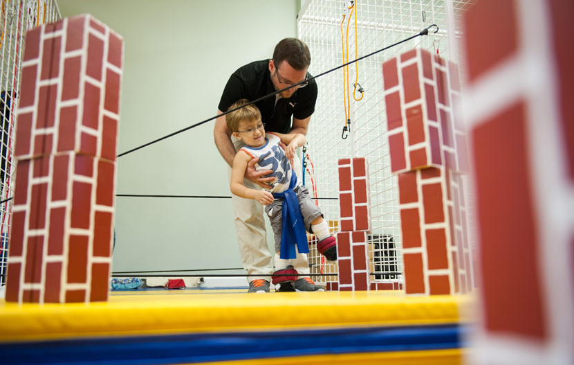 A man helps a young boy with spina bifida walk. 