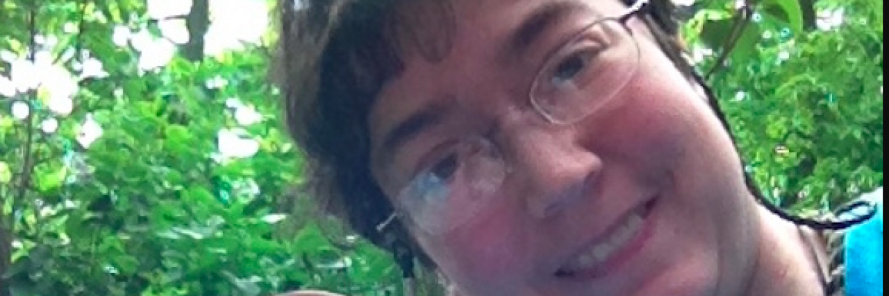 What I Want People to Know About Living With Gastroparesis Contributor, a woman with short hair and glasses, outside on a deck surrounded by trees