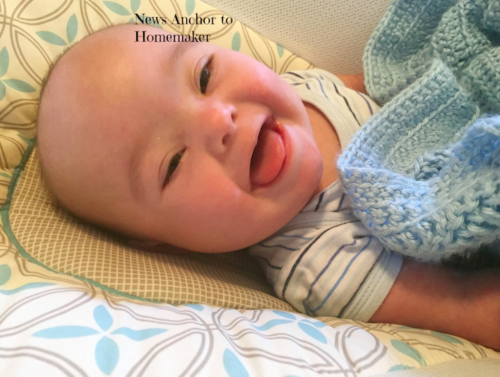 baby smiling while lying down with a knit blanket