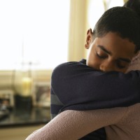 Boy (12-13) hugging mother at home
