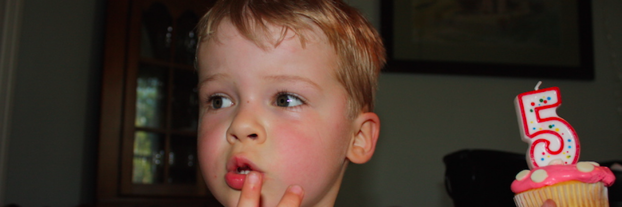 How My Son's Type 1 Diabetes Helps Us Celebrate Young boy holding a cupcake with a "5" candle on it