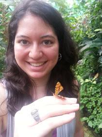 A woman with a butterfly that landed on her finger. 