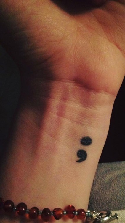 A tattoo of a semi-colon on a wrist