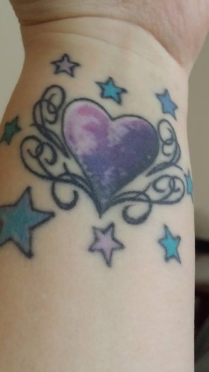 Tattoo of a purple heart surrounded by light purple and blue stars