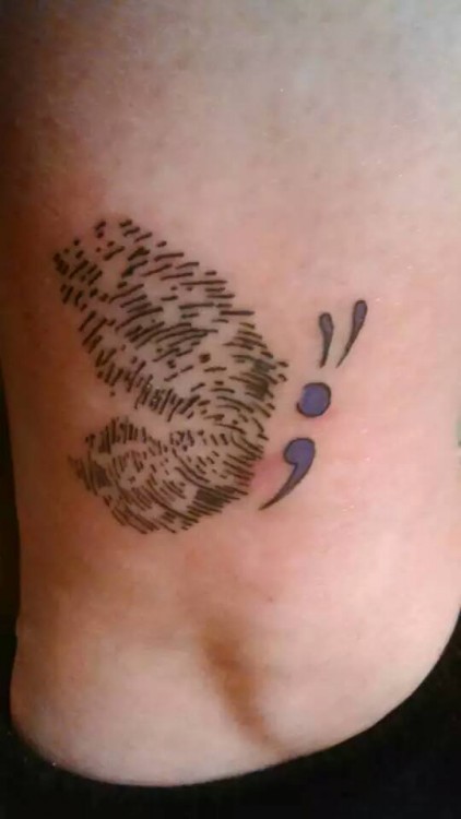 A tattoo of a combination of a semicolon and a butterfly with fingerprints as the wings