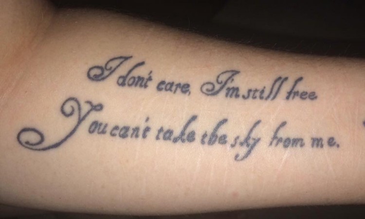 A tattoo of the words, "I don't care, I'm still free. You can't take the sky away from me."