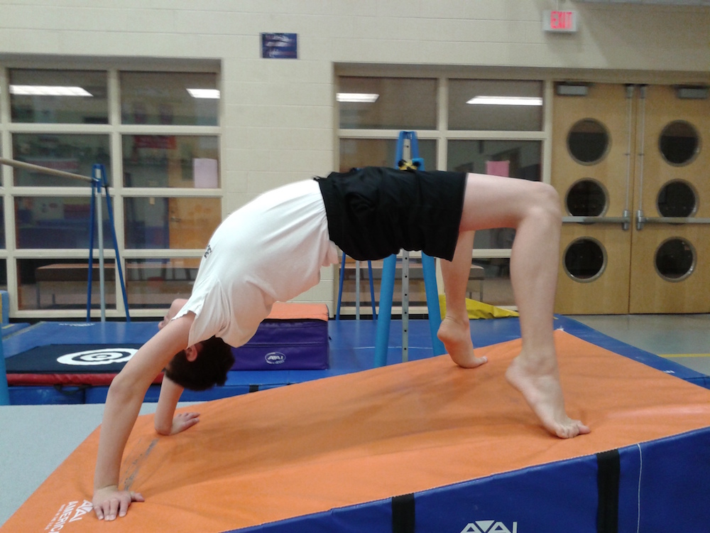 boy doing backbend in gymnasium