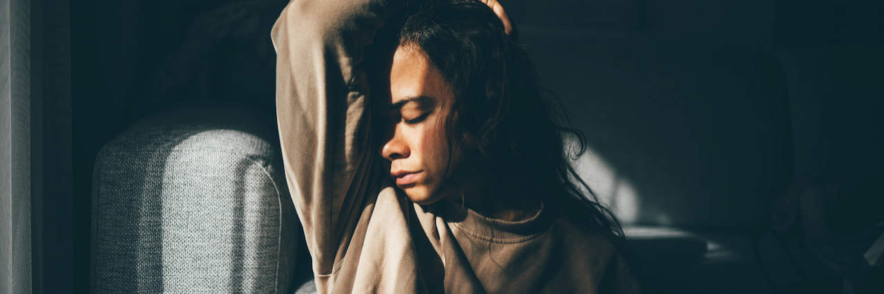 A Letter to Someone Who Thinks Fibromyalgia Isn’t Real A woman sitting in front of her couch with her hands above her head