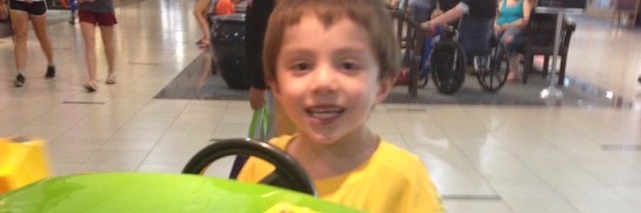 Mother Shares Photo of Her Special Needs Son Smiling and Playing young boy smiling and playing on a ride at the mall