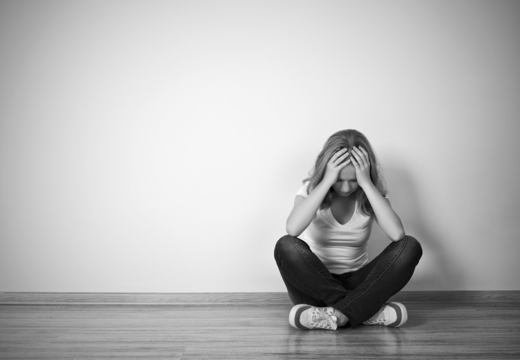 girl sits in depression on floor near the wall