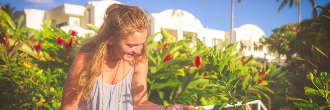 To the Friends I've Lost Because of My Depression Young woman outside in garden holding a sunflower