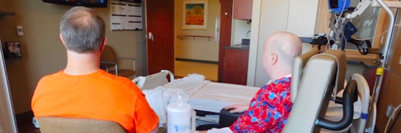 The Secret I Want to Share After My Son With Autism Was Diagnosed With Cancer Father watching TV with older son in hospital
