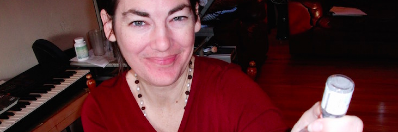 What I Didn't Expect to Feel as a Full-Time Caregiver Contributor holding medicine and syringe at home and smiling