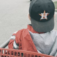 a boy with a backwards cap sits in a grocery cart
