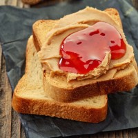 Peanut butter and strawberry jelly sandwich on wooden background
