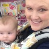 Mom smiles at camera with two babies strapped to her