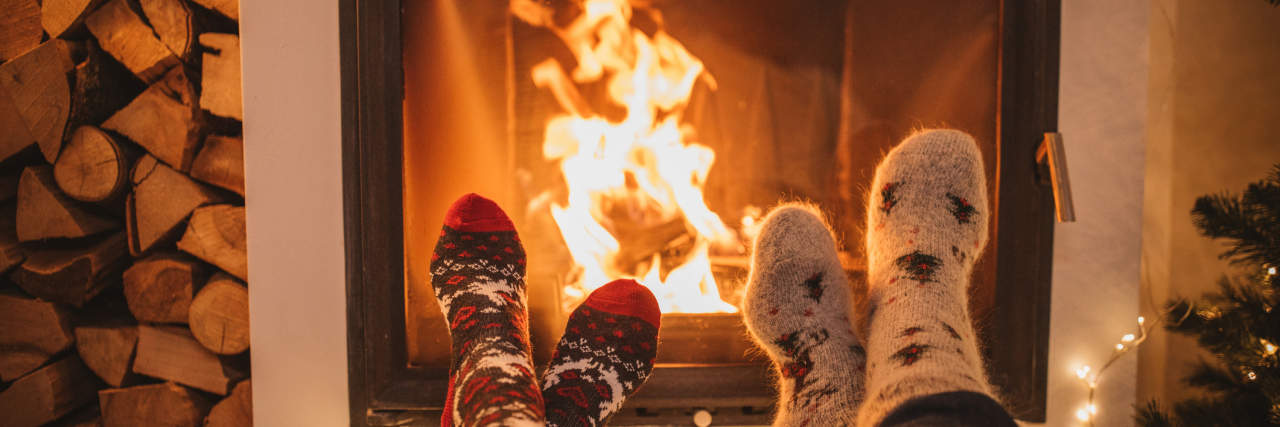 Things You Don't Have to Do During the Holidays Lazy winter day in front of fire in fireplace. Human legs in Christmas socks in front of fireplace.