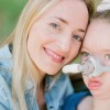 Mom smiles with young daughter who has tube attached to her face