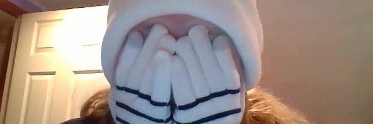 Fibromyalgia: How It Feels to Have 'Fibro Fog' The author wearing a hat and gloves while covering her face with her hands