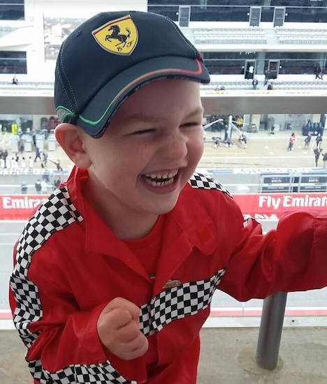 young boy laughing and wearing racing gear