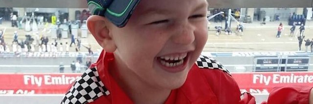 young boy laughing and wearing racing gear