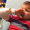 Toddler boy lies on back with pacifier in his mouth