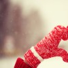 A person making a heart with their hands (which are in mittens)