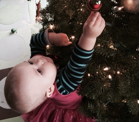 young girl hanging an ornament on a christmas tree