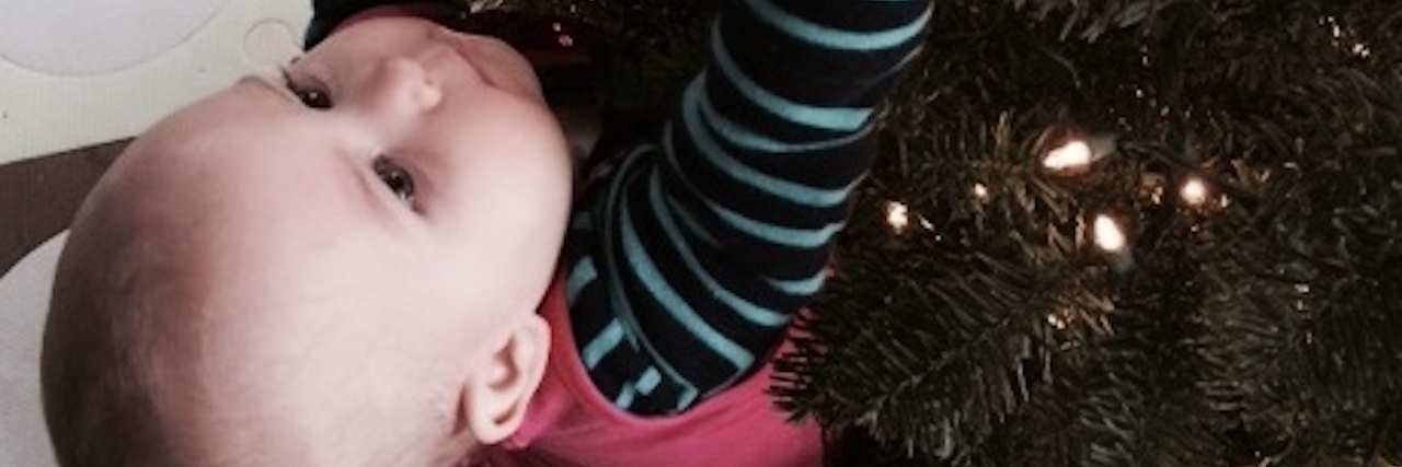 young girl hanging an ornament on a christmas tree