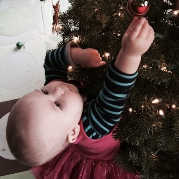 young girl hanging an ornament on a christmas tree