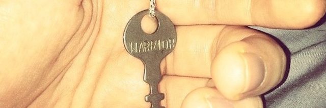 woman holding a key that says 'warrior'