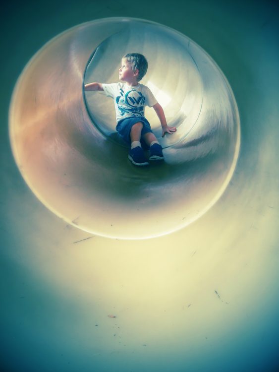 little boy playing in a slide