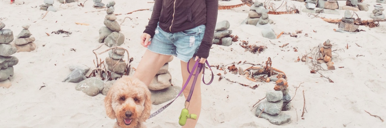 Woman With Lung Cancer Questioned If She Has ‘Real’ Service Dog Contributor standing with service dog on sand with rock piles behind them