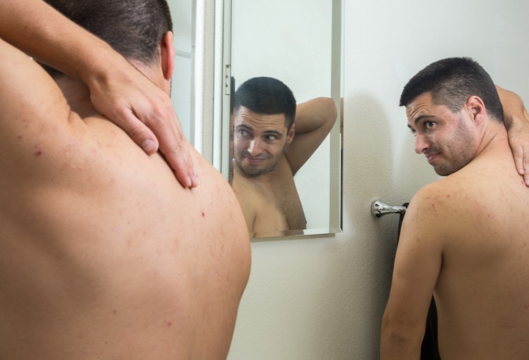 Man with OCD picking at skin in bathroom