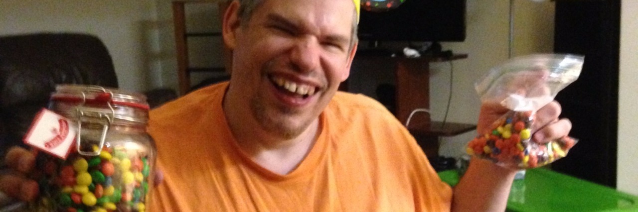 Befriending Man With Cerebral Palsy and Bonding Over Candy Jar mandy's friend bill in an orange shirt and hat holding jars of candy