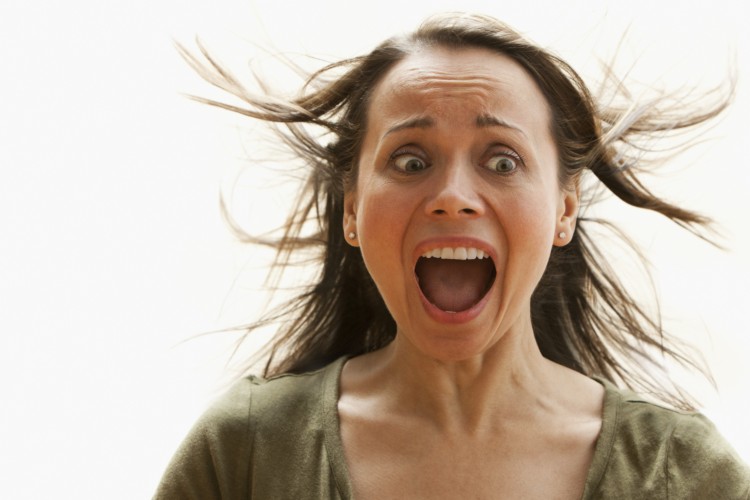 Scared woman screaming with hair blowing