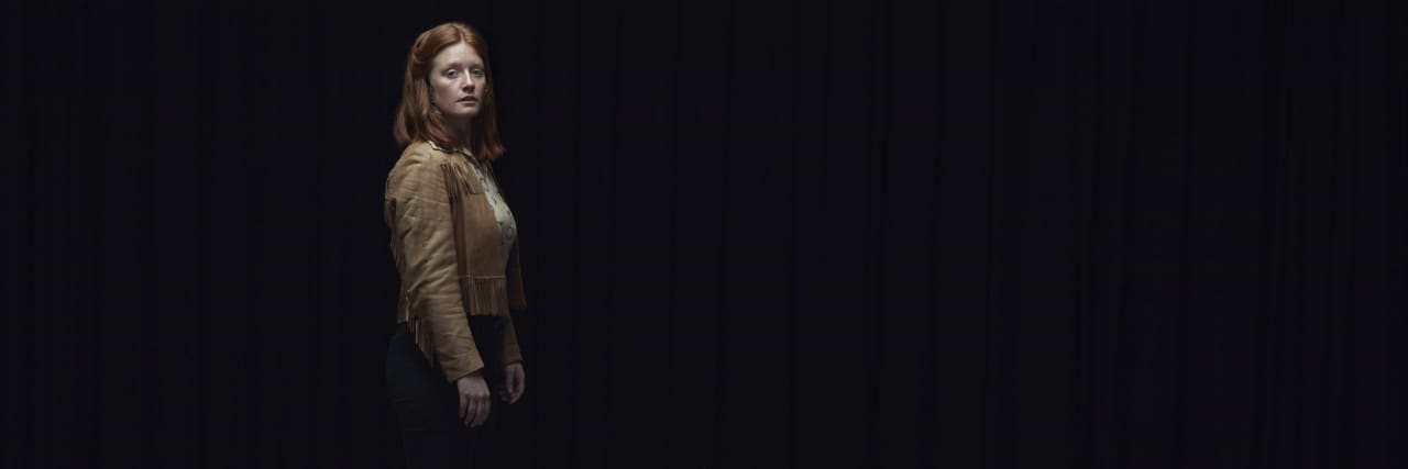 a woman standing alone in a dark room