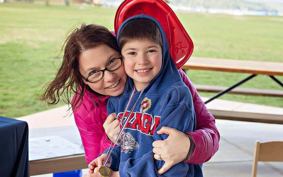 mom and son smiling for the camera in a park