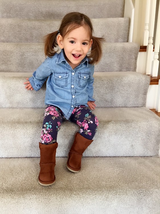 Little girl with pig-tails smiles on staircase in home