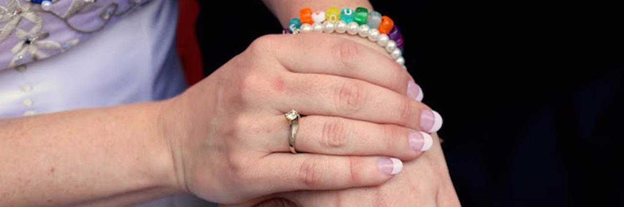 Close up on Sarah's hands. Her bracelet says, "I love you."