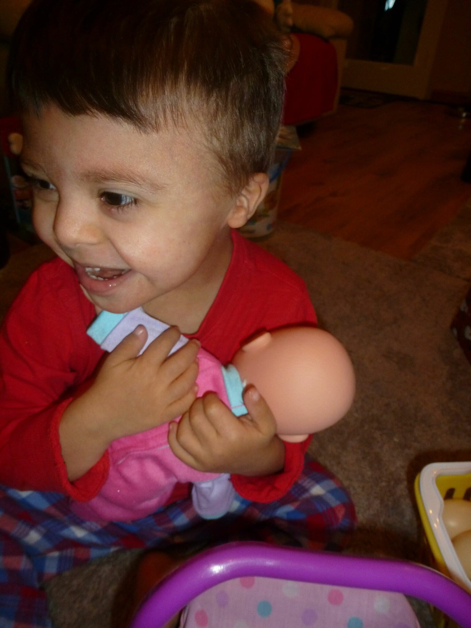 Why We Have Such Great Expectations for Our Son With Down Syndrome little boy smiling while holding a babydoll