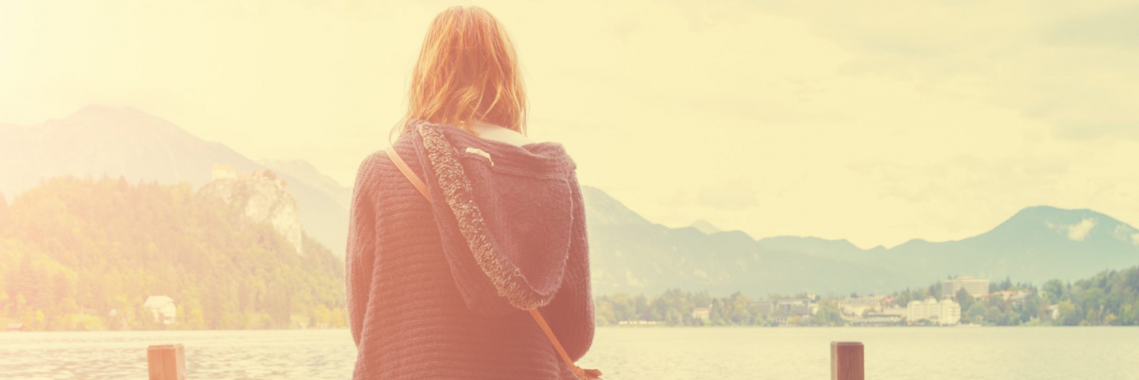 When the Pain That Comes With Lupus Is Unbearable Back view of woman sitting on a bench on a wooden pier overlooking water