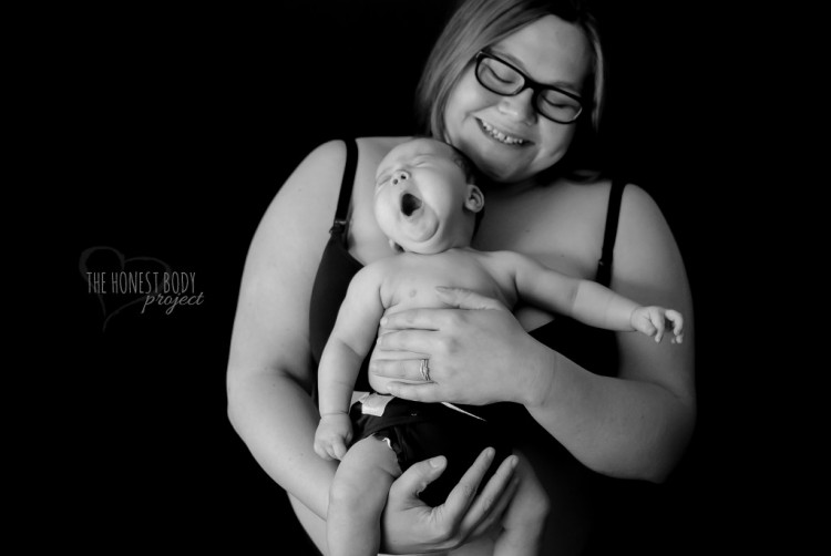 A woman smiles as she holds her yawning baby