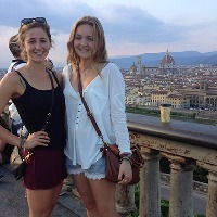 two women standing next to railing overlooking florence, italy
