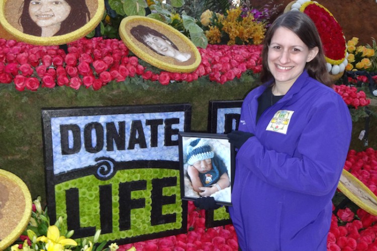 woman holding photo of baby in front of float